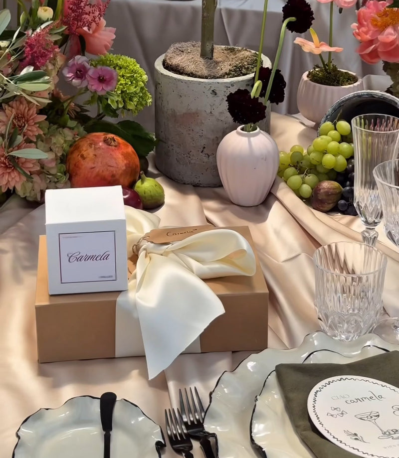 Decorative table setting with flowers, fruits, and elegant cutlery on a tablecloth.